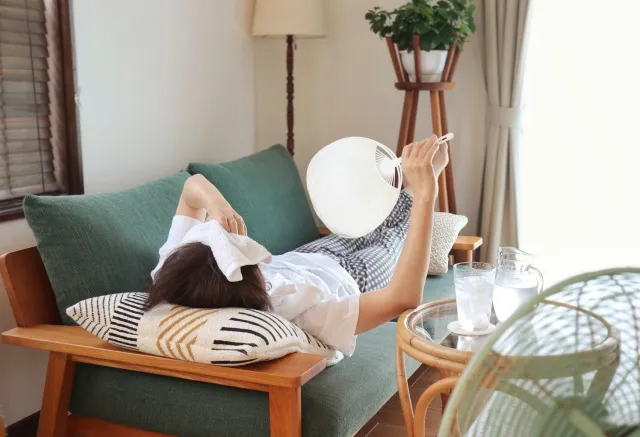 うちわで涼みながら疲れを癒す女性