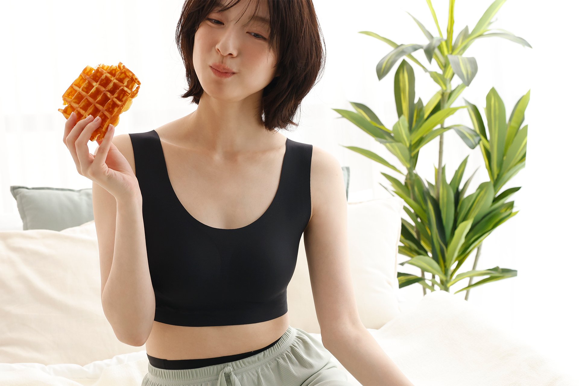 「肩らっくす SEAMLESS ハーフトップ」を着用しワッフルを手にする女性