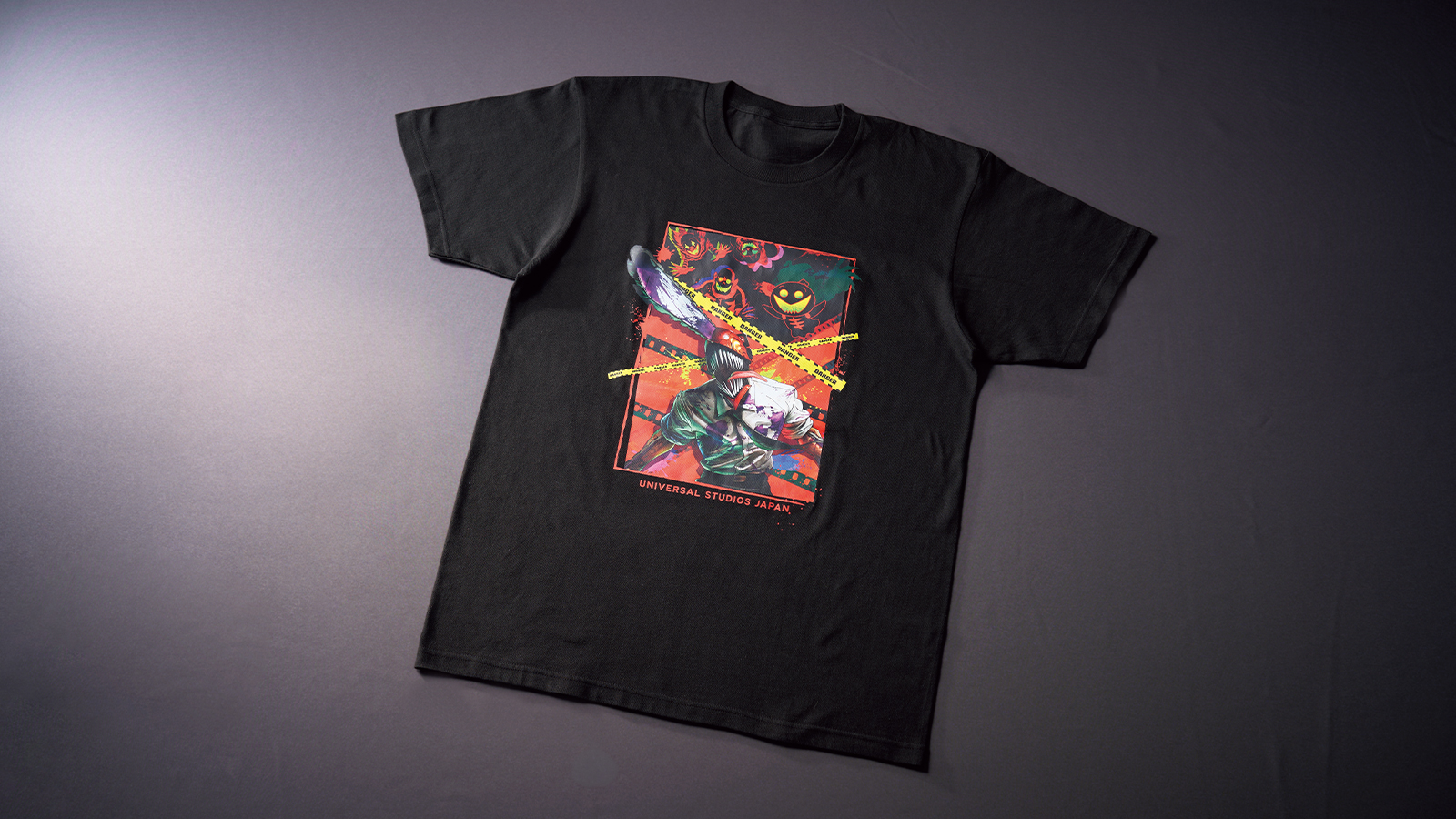 赤いパネルの中でチェンソーの刃を掲げるチェンソーマンをプリントした黒いTシャツ