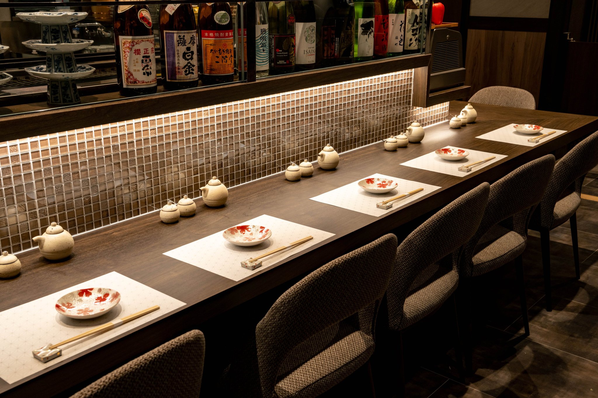 日本酒の一升瓶が並ぶ棚を背にしたカウンター席