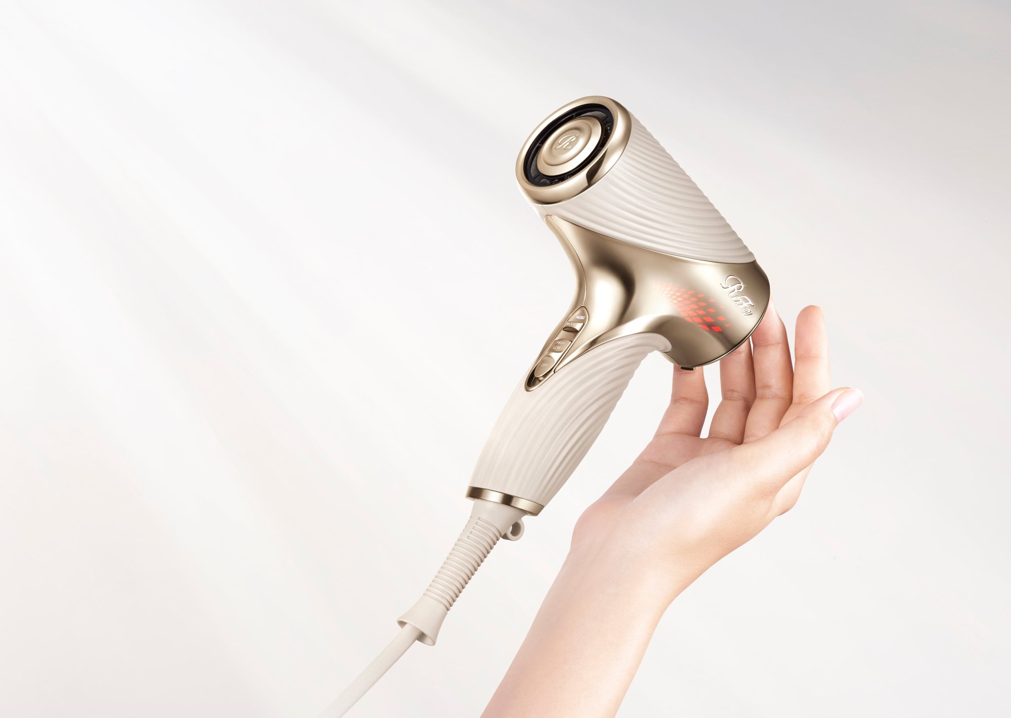 「ReFa BEAUTECH DRYER SE W」を手に持ちモード切替スイッチを操作する様子