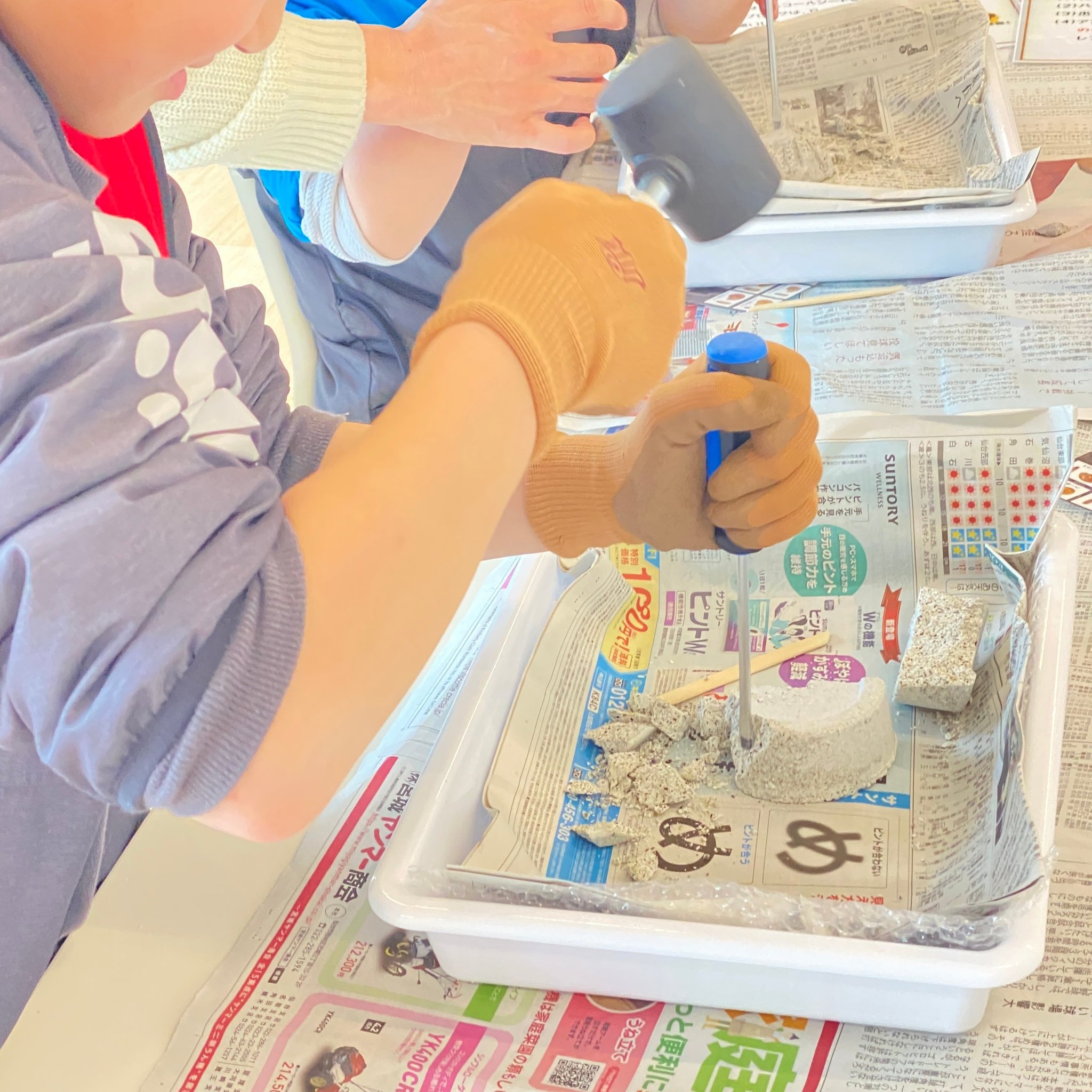 ハンマーと道具で岩ブロックを削る子どもの様子