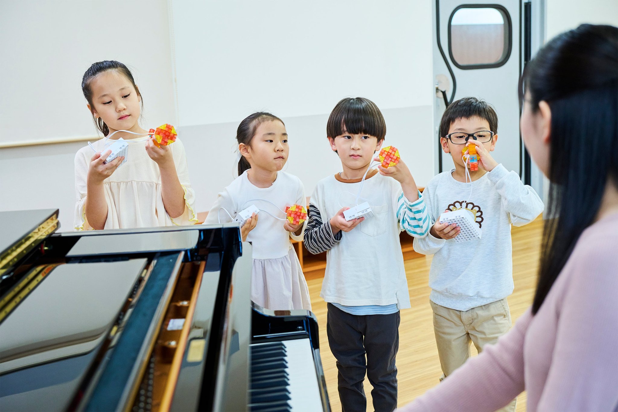 音楽とプログラミングを融合した学び：組み立てた作品を手にしてアンサンブルに取り組む子どもたち