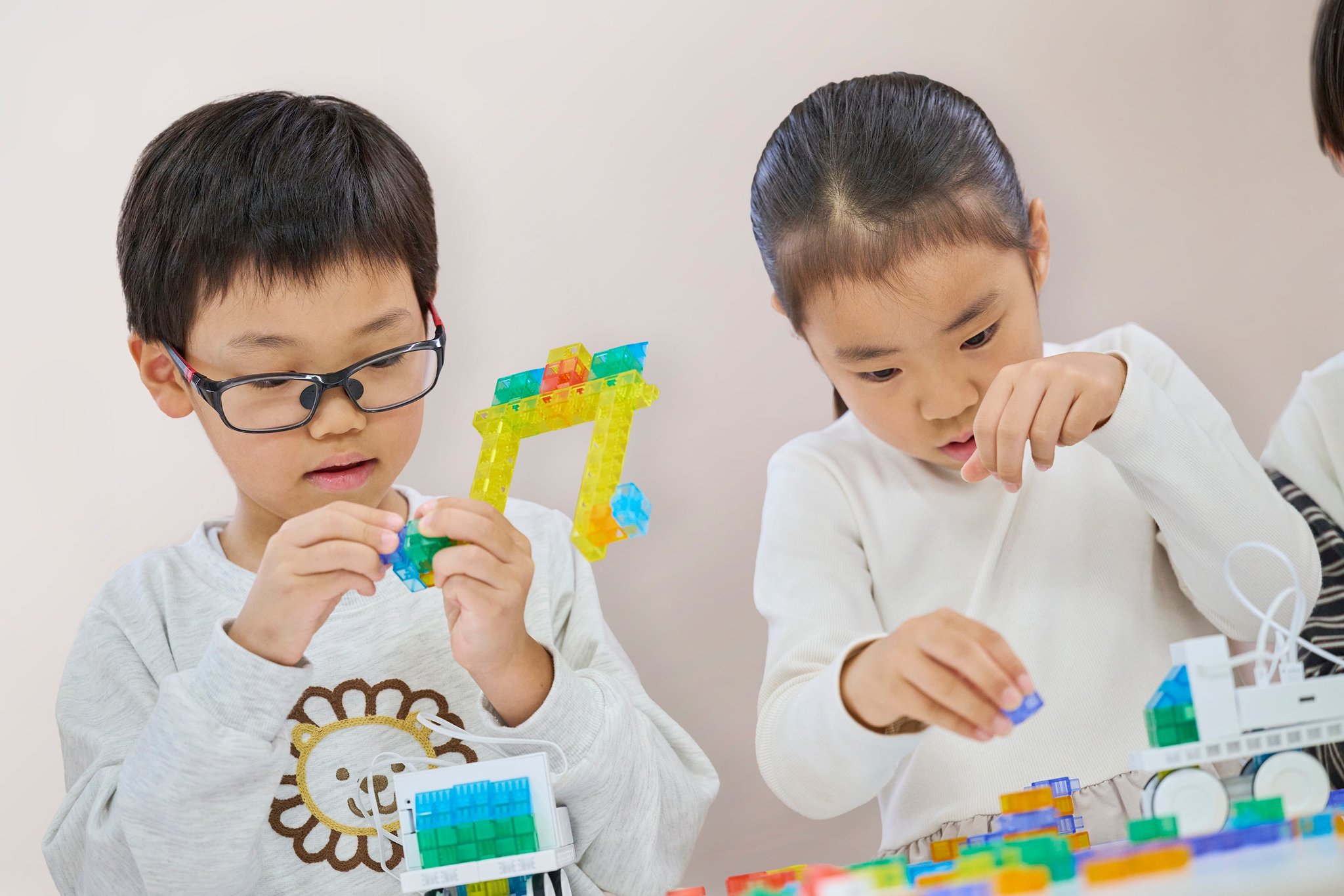 音楽とプログラミングを融合した学び：ブロックのパーツを手にしてロボットを組み立てる子どもたち