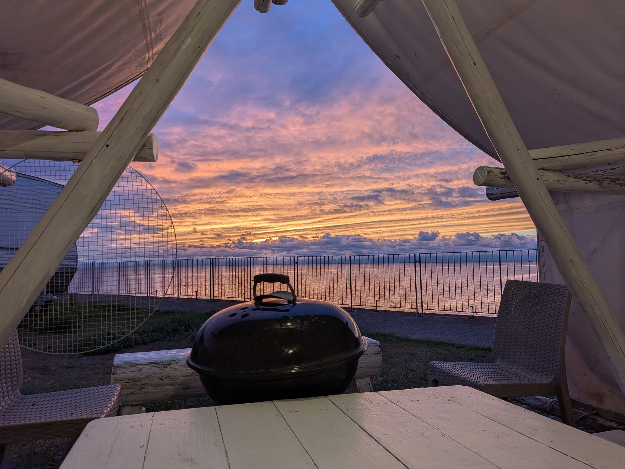 夕焼けの海を望むパーゴラと黒いケトルグリル