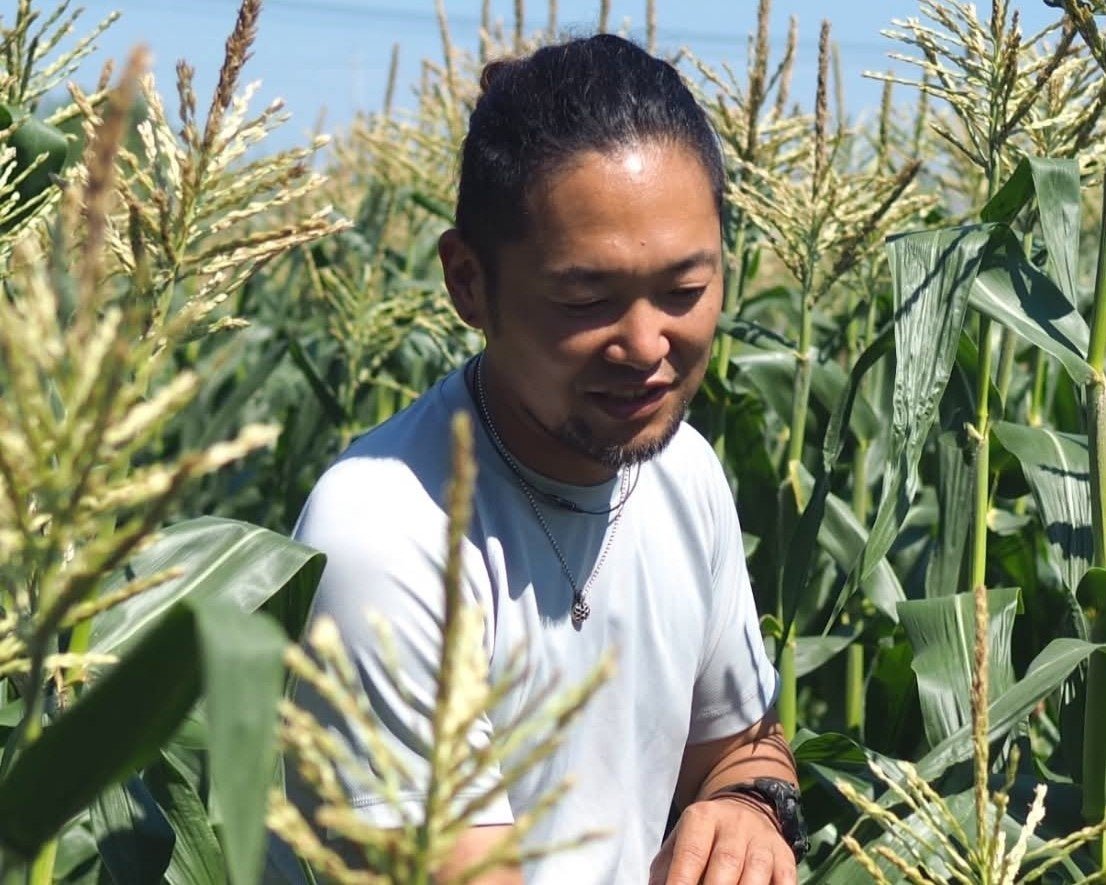 とうもろこし畑に立つ玉蜀黍儂人・彦坂航さん