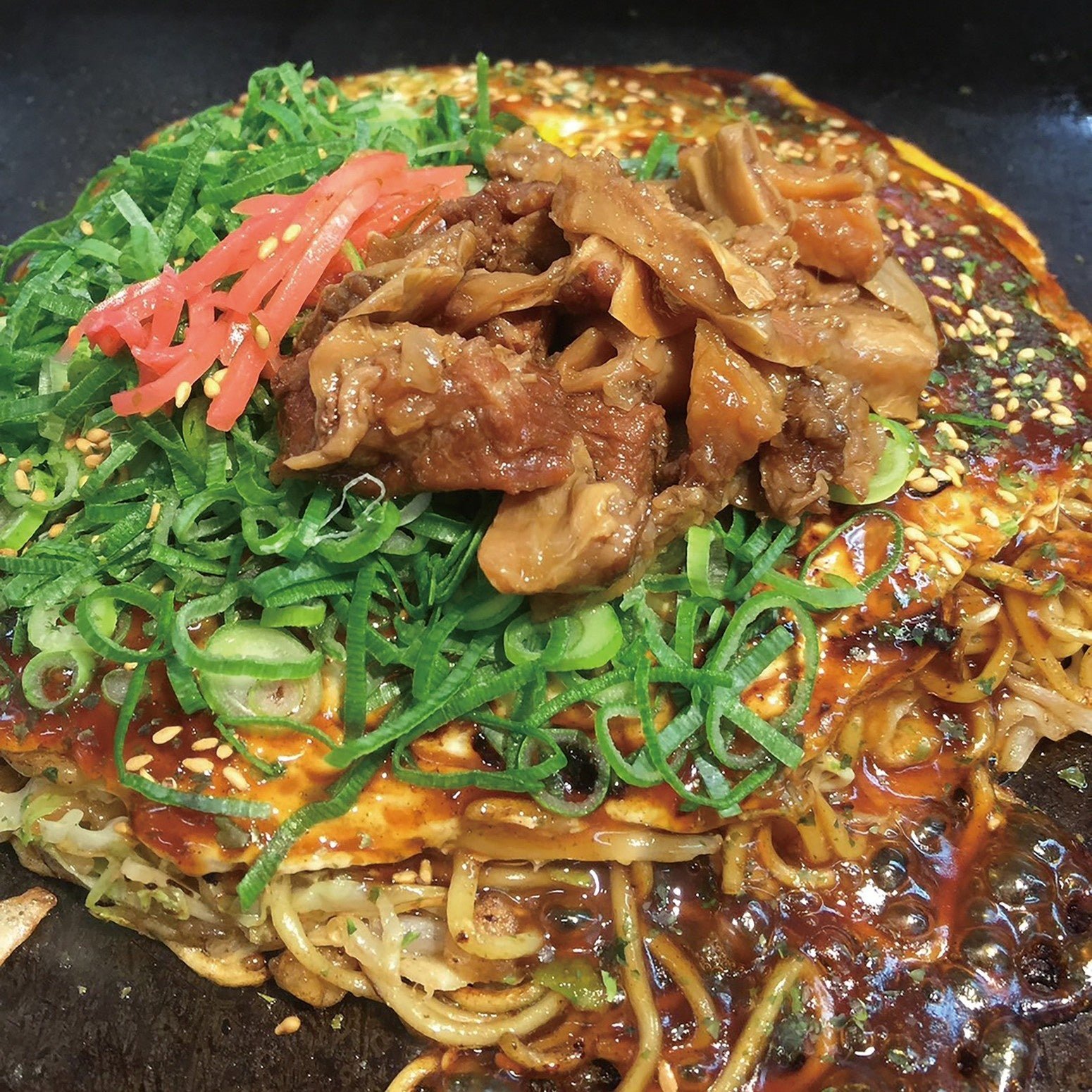 鉄板で提供される牛すじお好み焼き