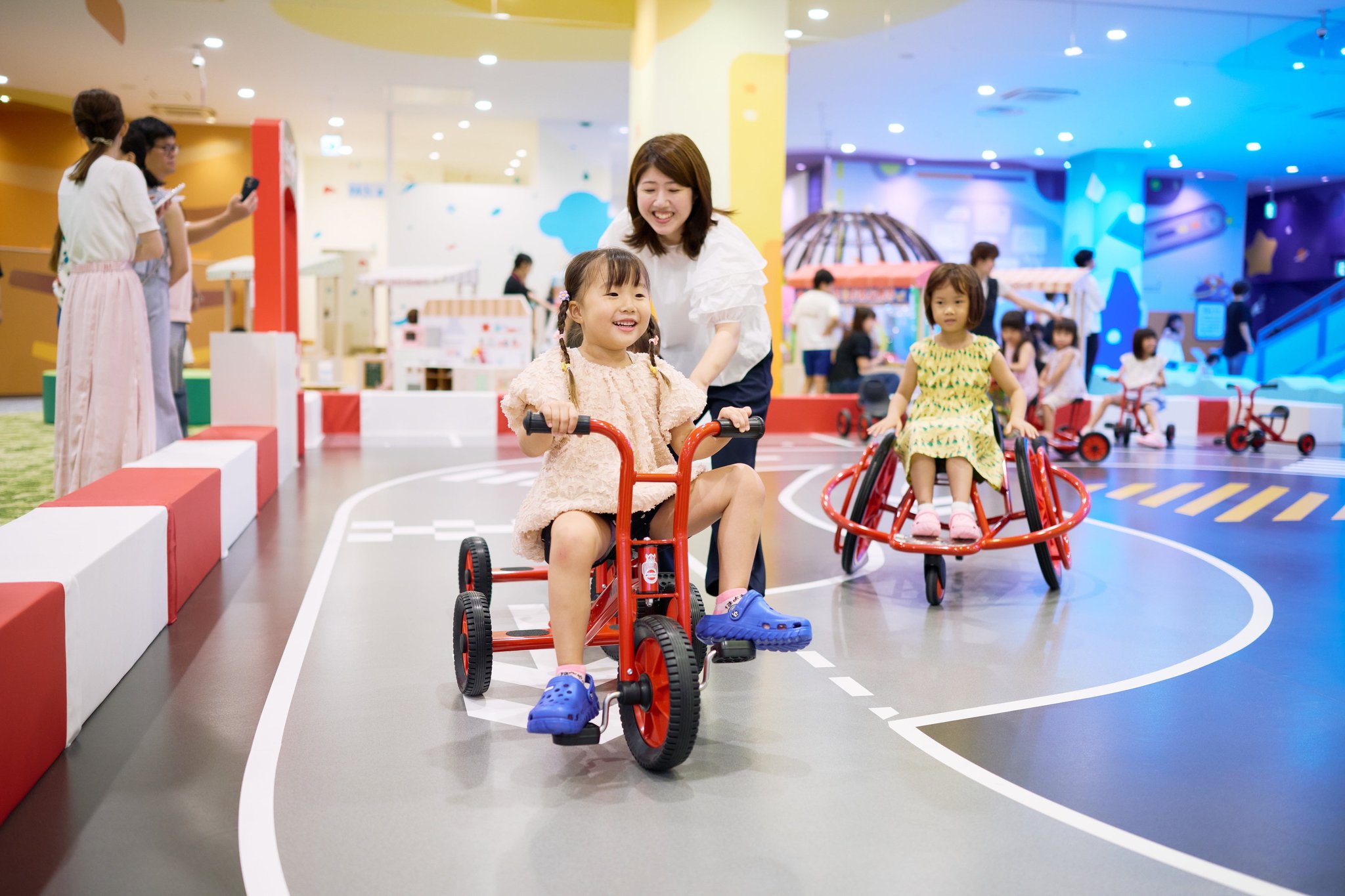 都市エリアで三輪車型の乗り物に乗る子ども