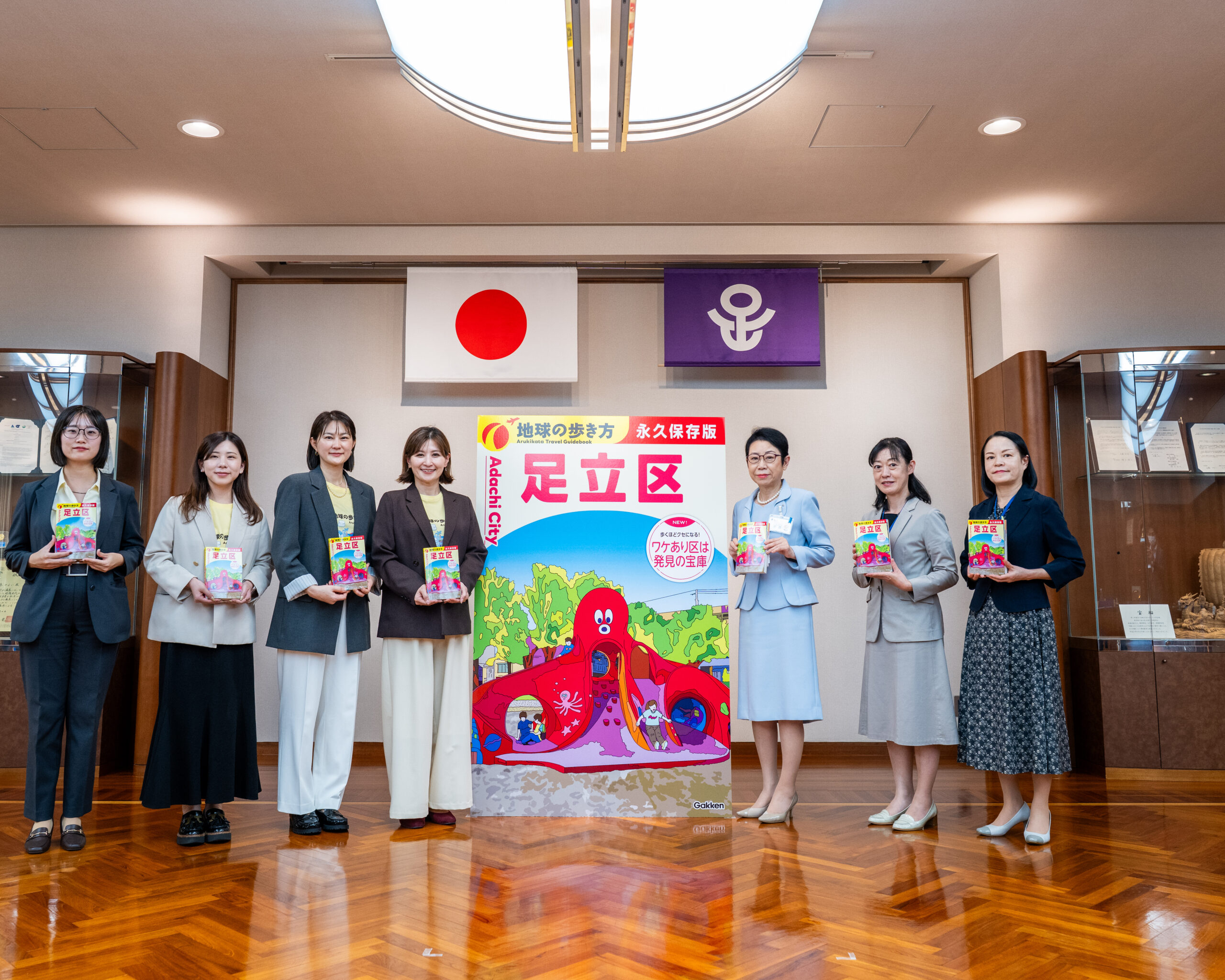 『地球の歩き方 足立区』大型表紙パネルを囲む表敬訪問の出席者