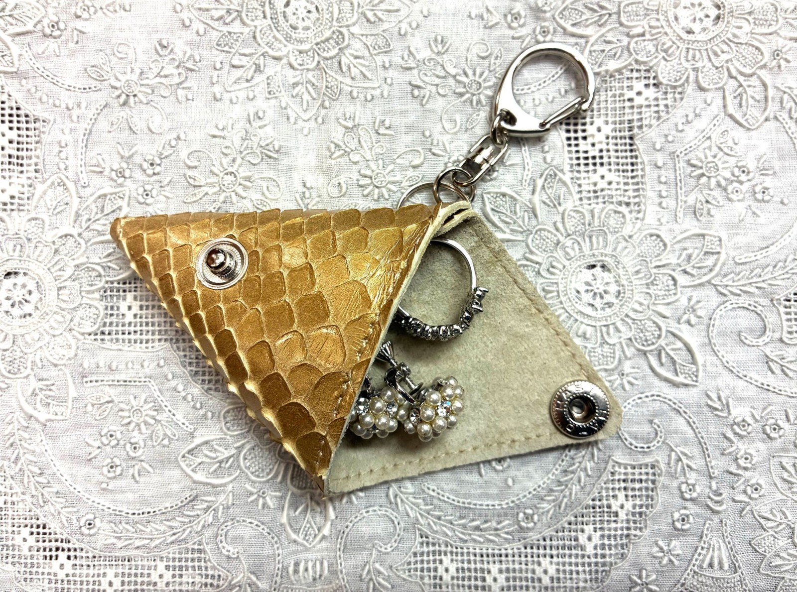 三角形の本革製チャームを開いてアクセサリーを収納した様子