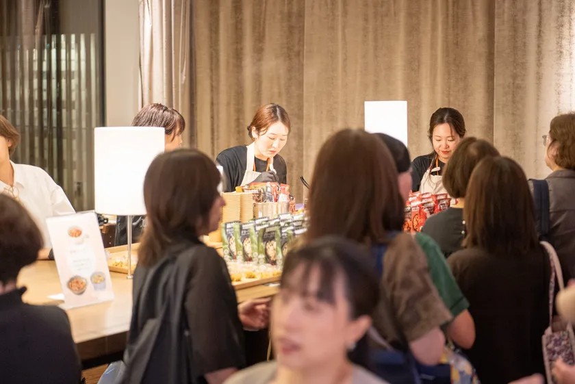 試食テーブルに集まる来場者と料理を提供するスタッフ