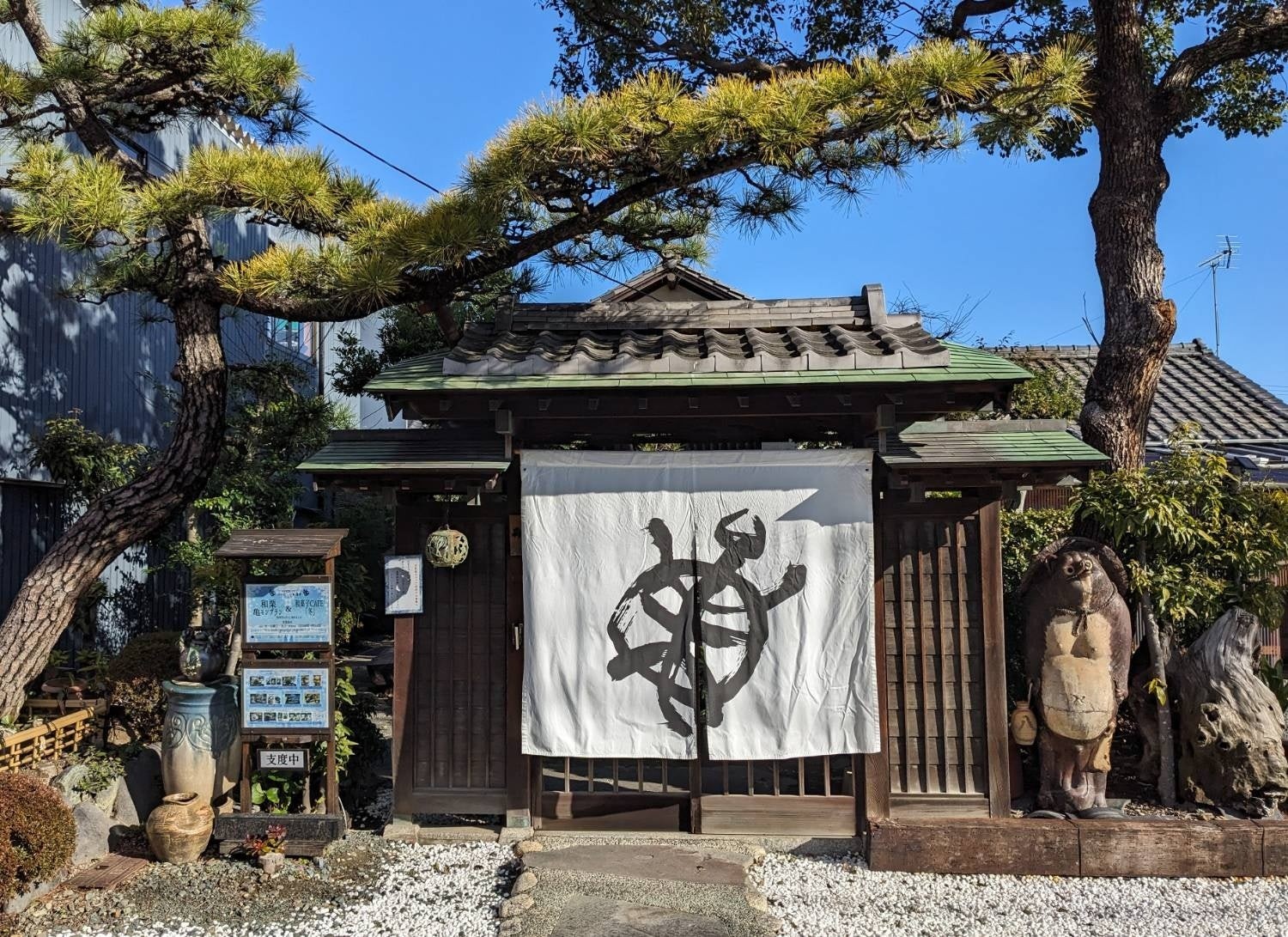 亀の絵が描かれた白い暖簾を掛けたお亀堂の入口、松の木と「支度中」の札