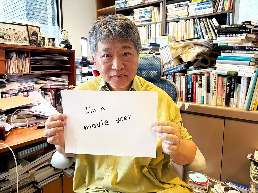 是枝裕和監督が「I'm a moviegoer」の直筆メッセージ入りボードを掲げる様子
