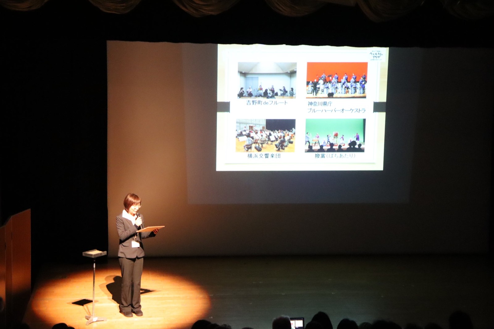 吉野町市民プラザのステージでスライドを使って紹介する様子