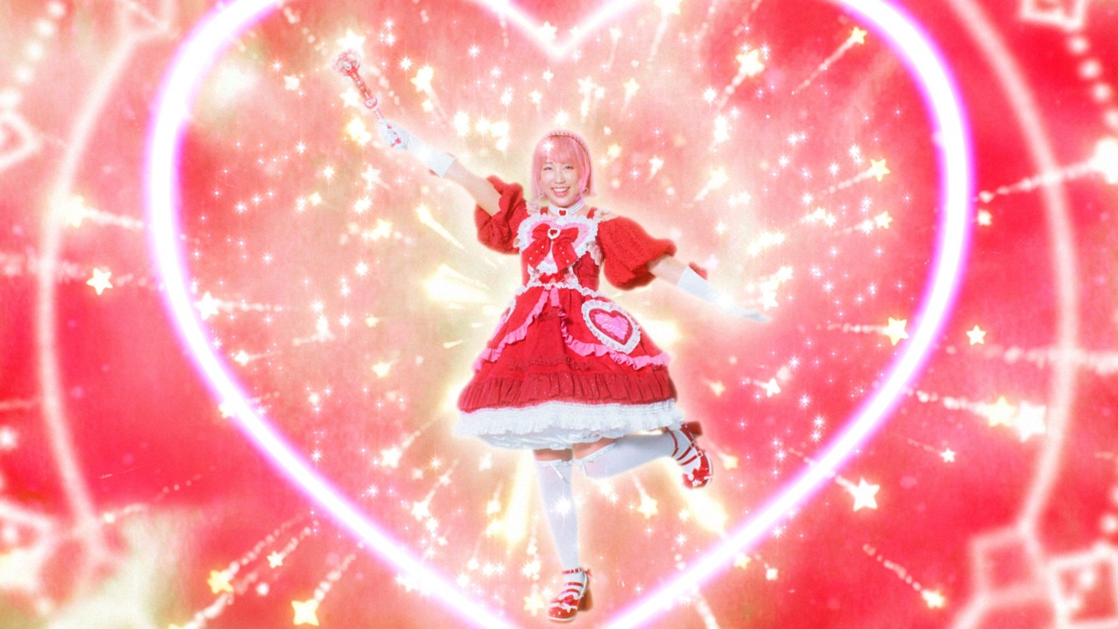 赤いドレスの魔法少女姿に変身した菅沼菜々選手がハート型の光の中でポーズを決めるシーン