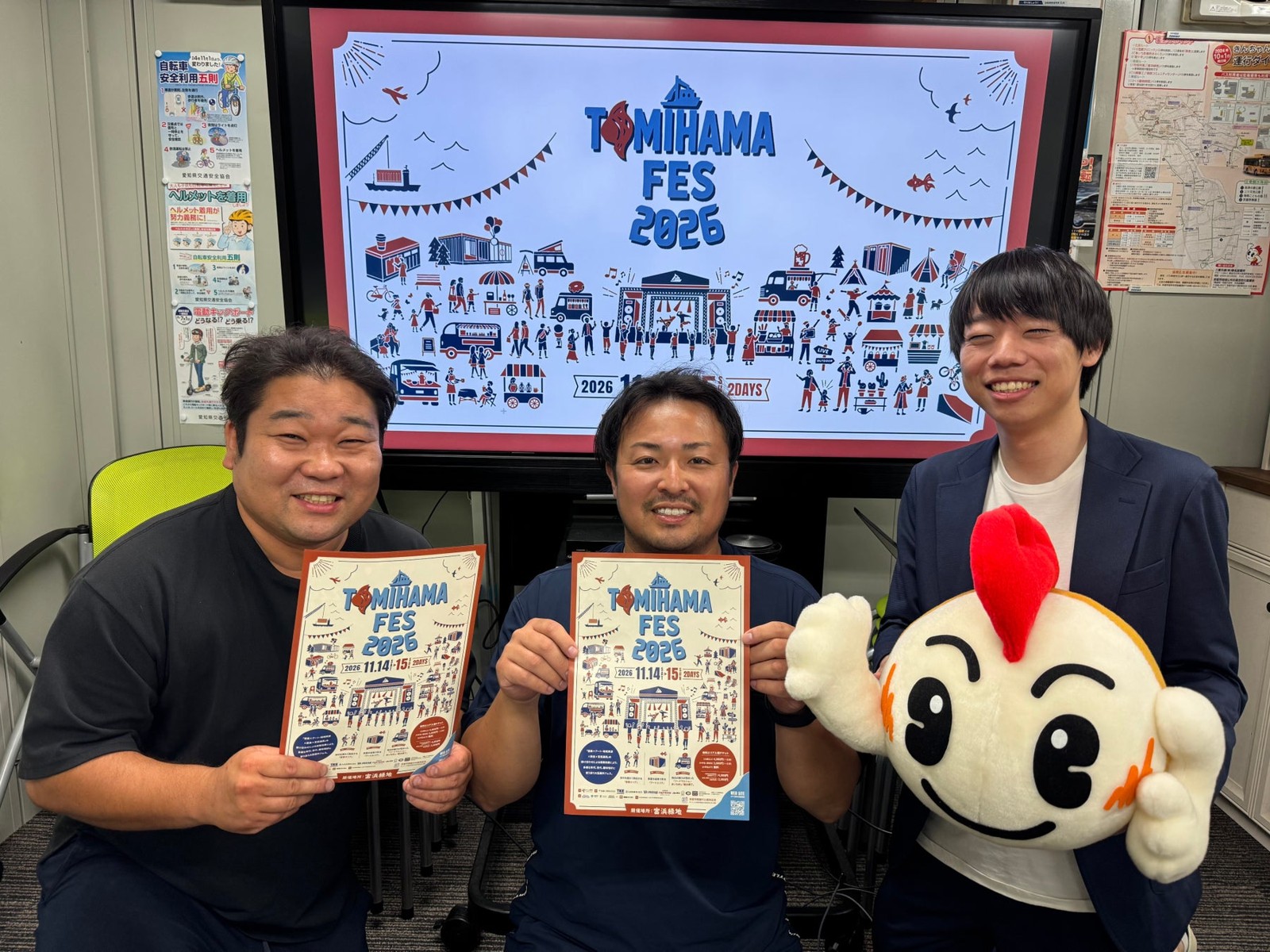 TOMIHAMA FES 2026 ポスターを手にする関係者とマスコット