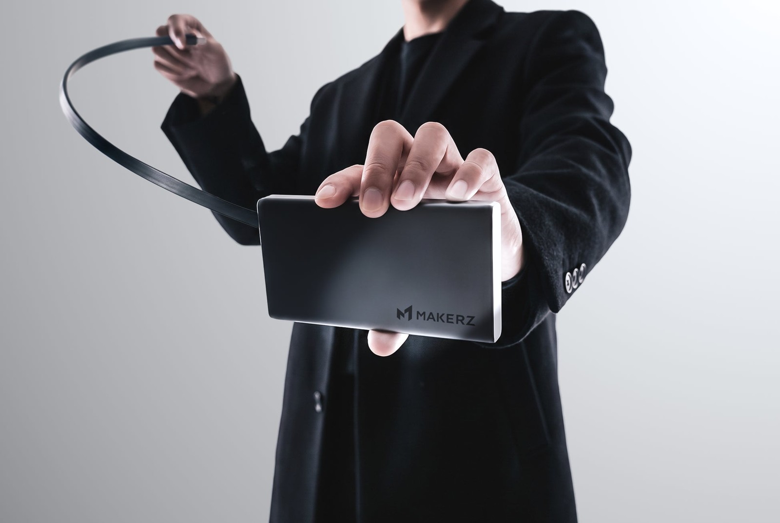 巻取り式ケーブルを引き出した「SOLIDZ Power Bank Model IT」を持つ手元