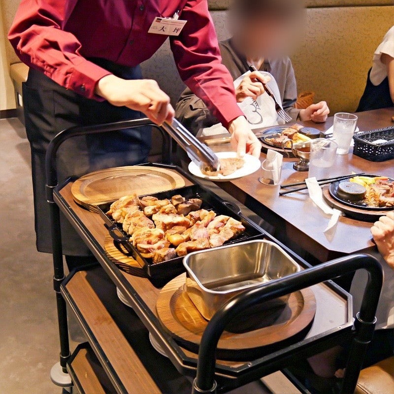 スタッフがトングでステーキを取り分けている様子