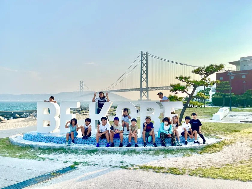 明石海峡大橋を背景にBE KOBEのモニュメント前で記念撮影する子どもたち