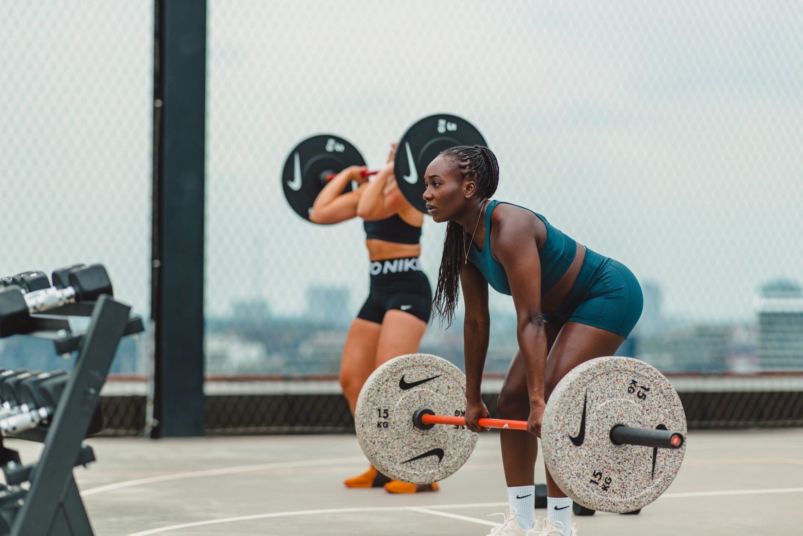 Nike Grind Bumper Platesを付けたバーベルを持ち上げる手前の女性
