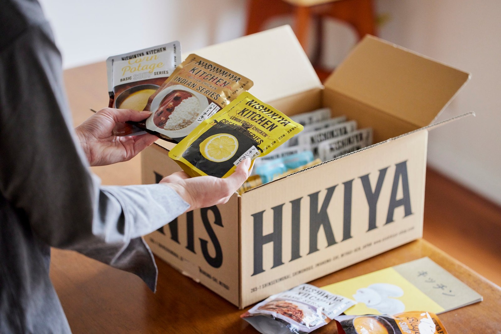 ニシキヤキッチンの箱からレトルト食品を取り出すお届けイメージ