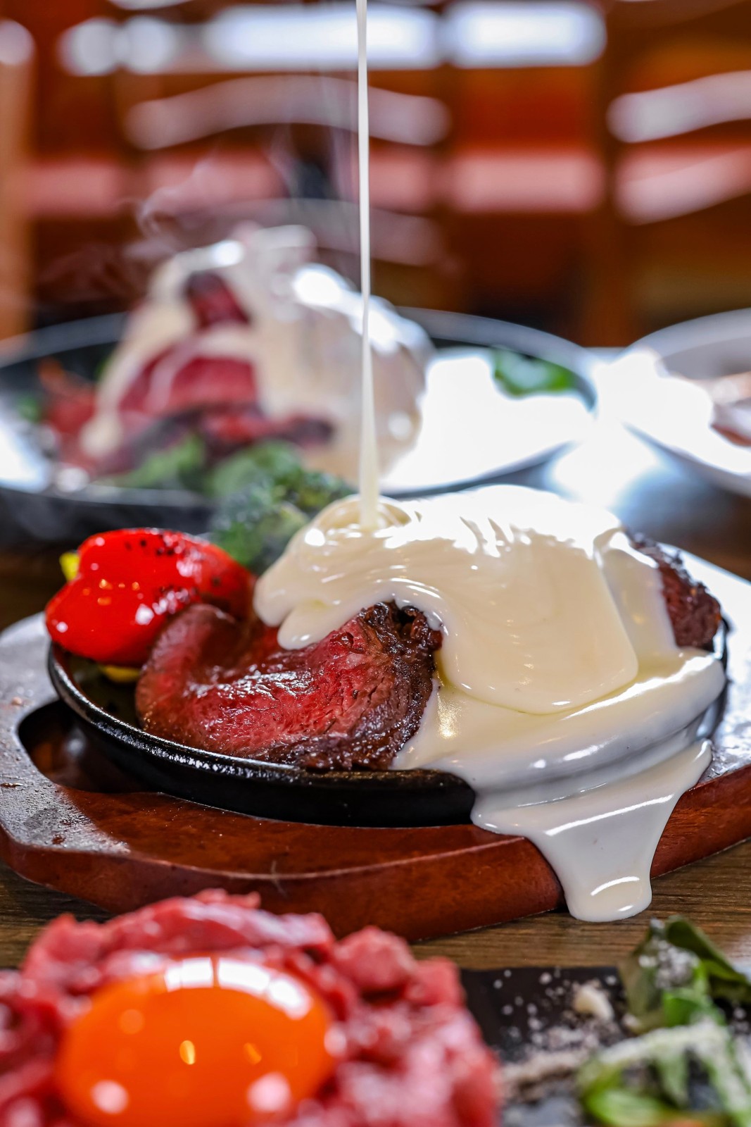 熱々の肉料理にチーズをかける様子