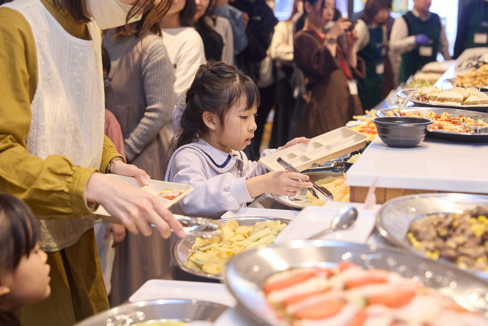 天ぷらをトングで取り分ける子ども