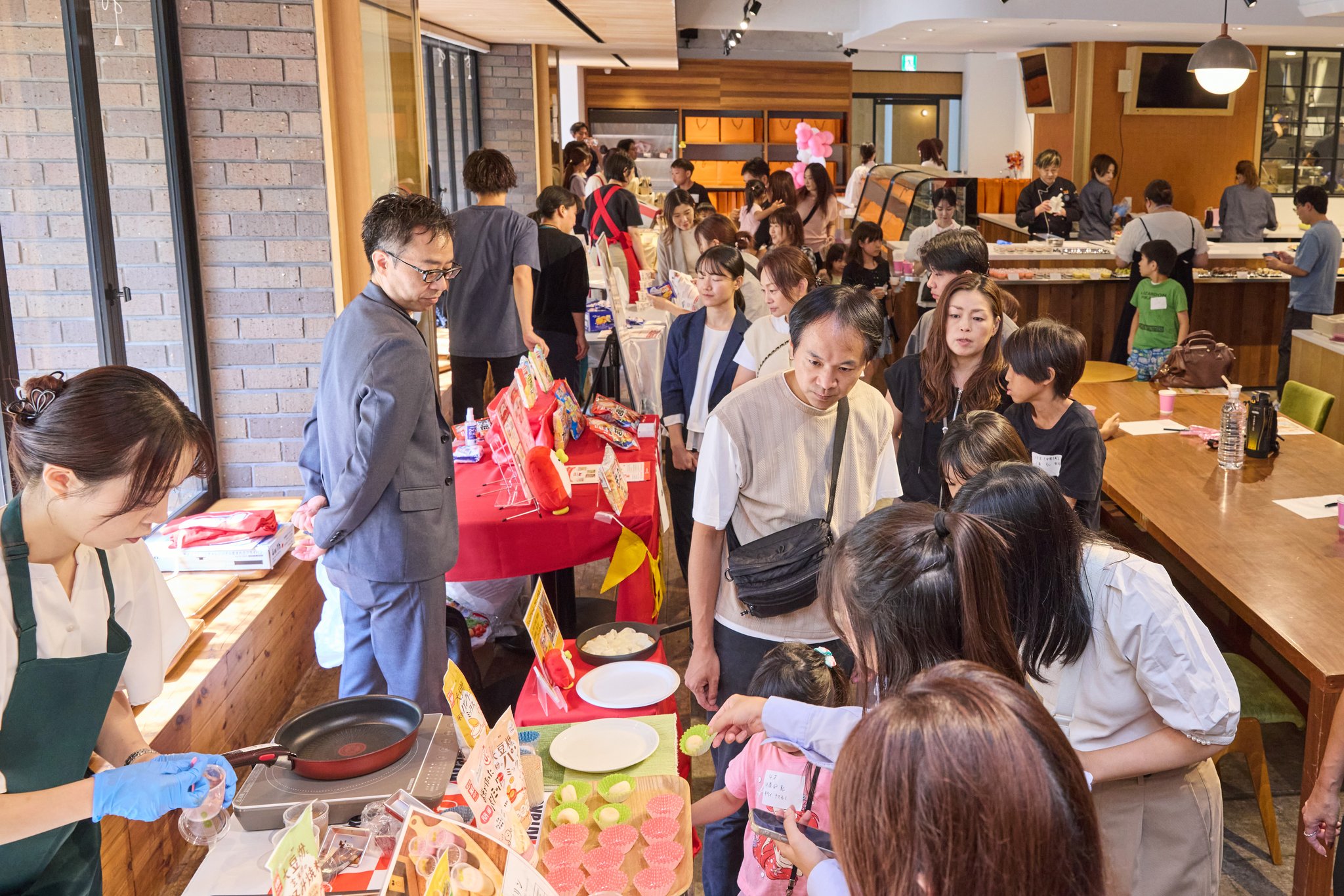 会場を見て回る来場者と試食ブース