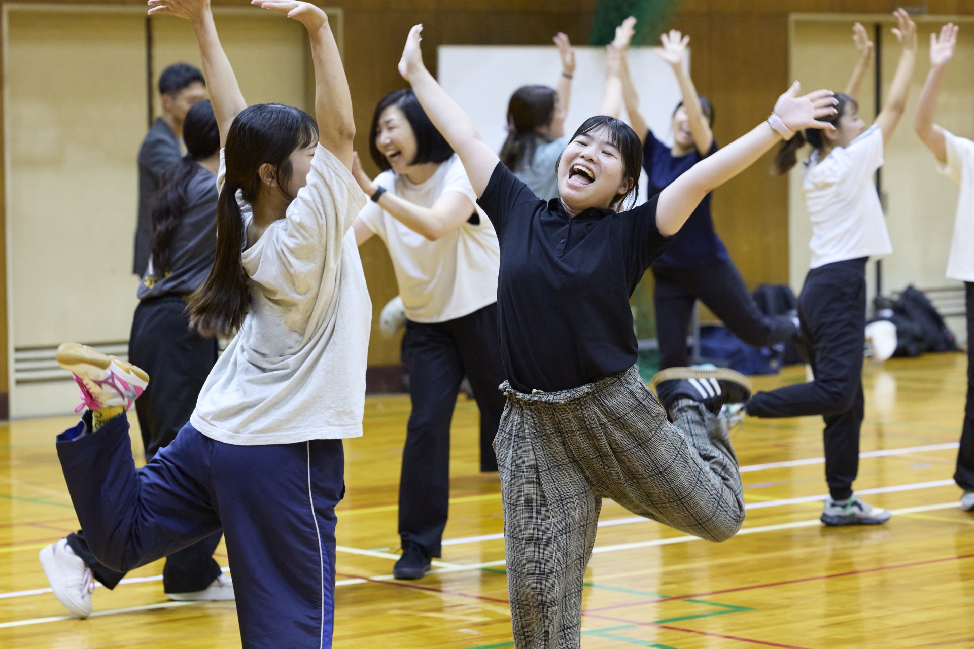 両手を上げて自由表現に挑戦する教員