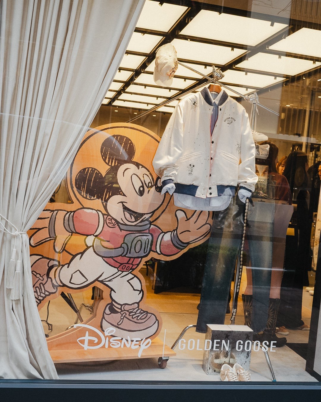 宇宙服姿のミッキーマウスのパネルとコラボ衣類の店頭展示