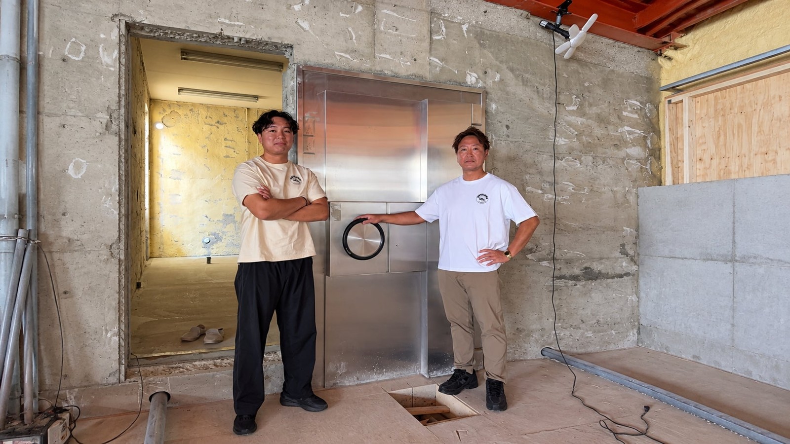 金庫扉の前に立つ2人