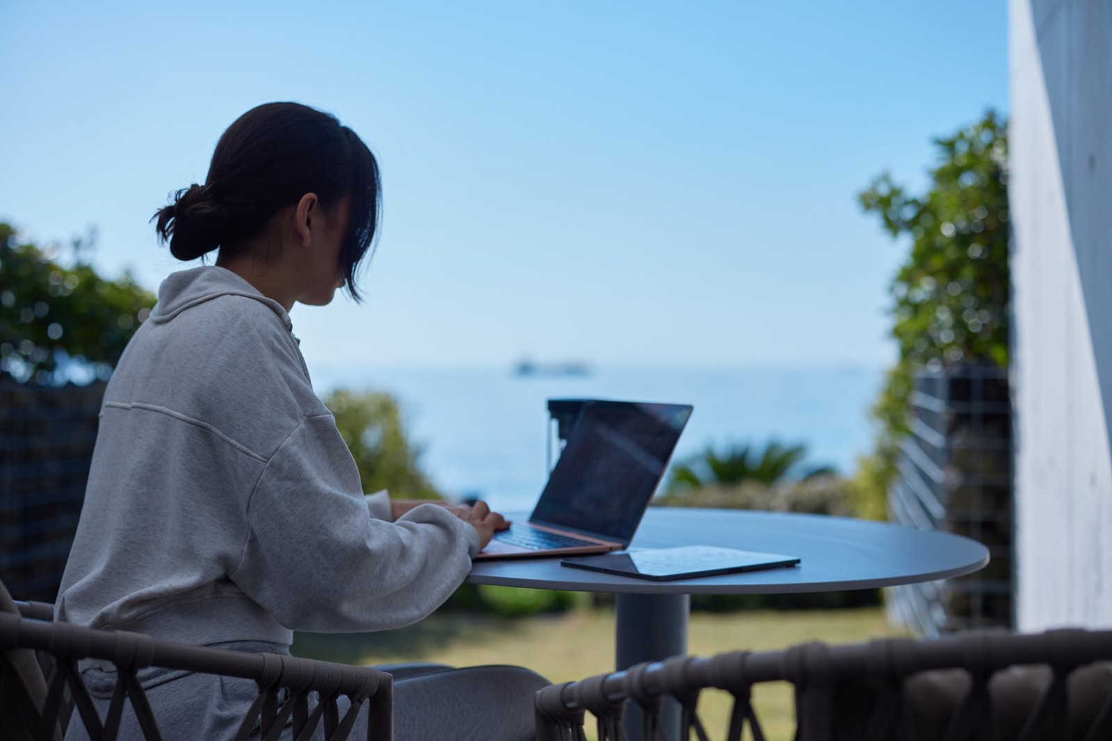 海を望む屋外テーブルでのノートパソコン作業