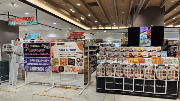 アンニョンマートの店頭に掲示されたNEXT K-FOODの日本初上陸ポスターと商品陳列台