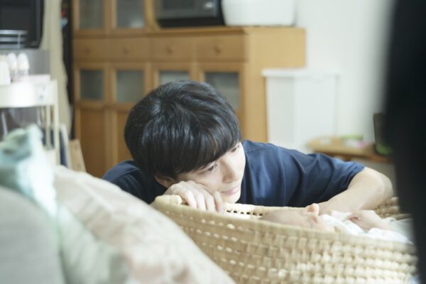赤ちゃんを見つめる将一の場面写真